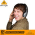 A smiling man wearing Zoso Music Behringer HPM1000 closed-back headphones for podcasting and audio monitoring