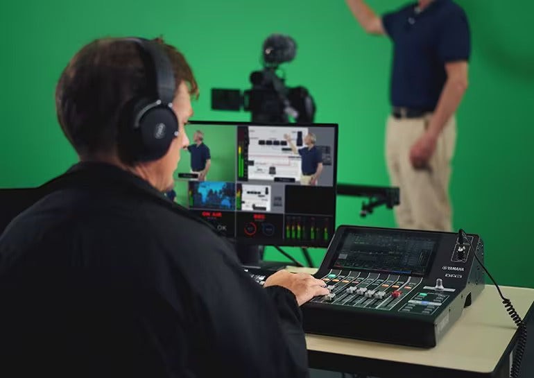 Zoso Music operator using a Yamaha DM3S 22-channel digital mixer with a 9-inch touchscreen in a green screen studio.