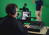 Zoso Music operator using a Yamaha DM3S 22-channel digital mixer with a 9-inch touchscreen in a green screen studio.