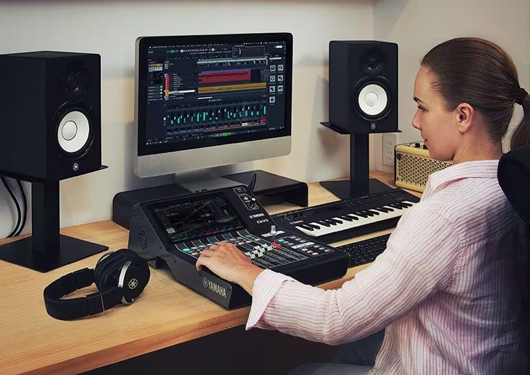 Zoso Music user operating a compact Yamaha DM3S 22-channel digital mixer in a home studio setup with monitors.